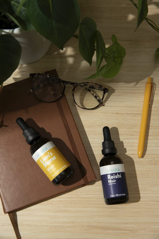 The AHARA Lion's Mane and Reishi Elixirs on a desk with a notebook