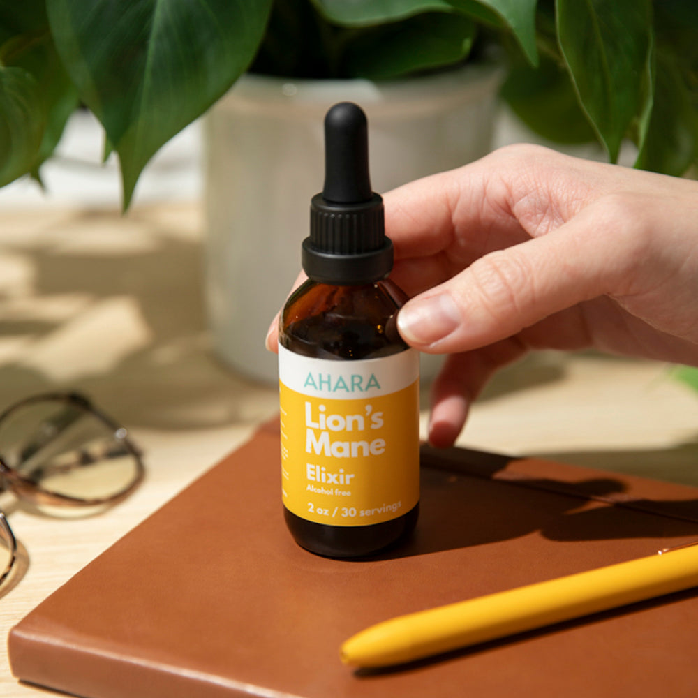 AHARA Lion's Mane Elixir bottle held over a notebook